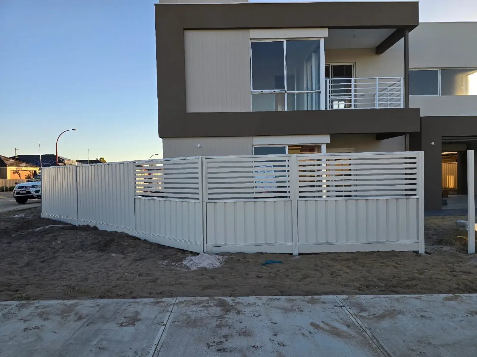 A white slat-top fence on a modern home