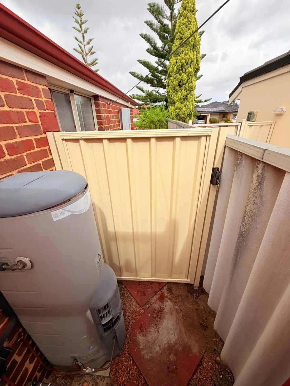 A cream Colorbond gate beside a home