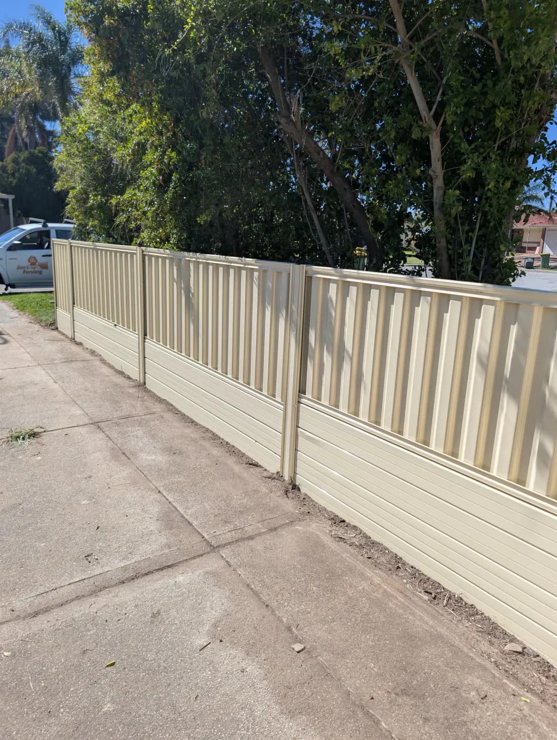 A cream Colorbond fence along a footpath